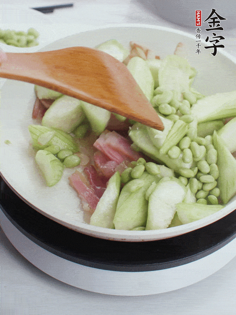 依次下絲瓜、青豆翻炒，炒至絲瓜打蔫縮小。