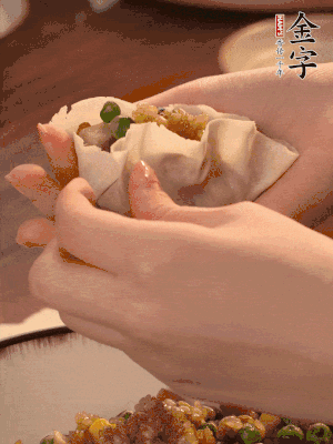 取一大勺餡料放進(jìn)餃子皮里，用大拇指按住頂部餡料，再用虎口掐出形狀。