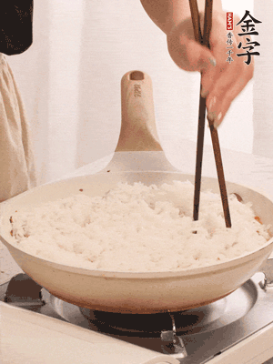 把瀝干水分的米飯均勻鋪在上面，筷子戳幾個洞，以便透氣，轉(zhuǎn)小火蓋上蓋子燜至水分收干，大概10分鐘。