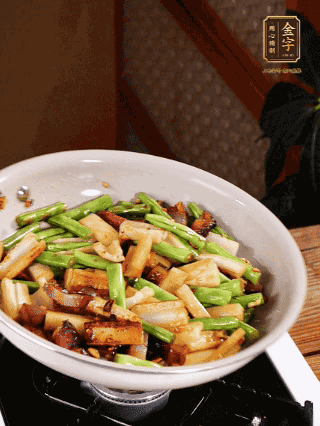 油熱下蒜末、干辣椒、醬肉煸炒出香味，依次下藕條、豆角翻炒均勻